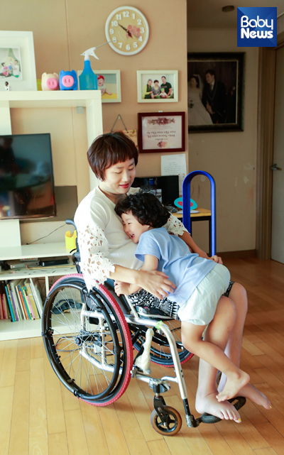 아내 이찬숙 씨. 역시 교통사고로 경추를 다친 장애인이다. 둘째 딸이 휠체어를 탄 엄마의 무릎 위로 올라가 안겼다. 최대성 기자 ⓒ베이비뉴스