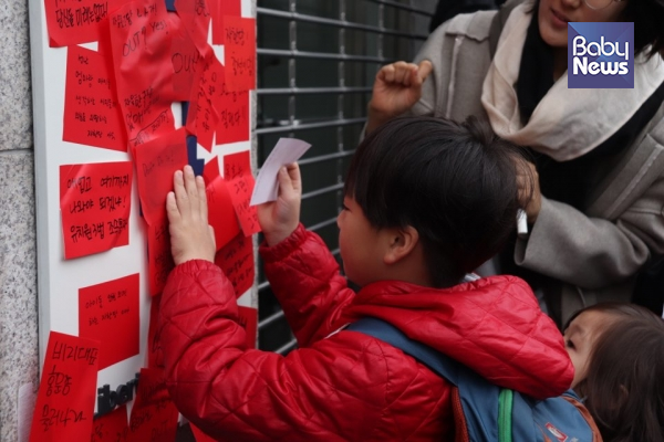 빨간 메모지를 자유한국당 간판에 붙이는 아이의 모습. 이중삼 기자 ⓒ베이비뉴스